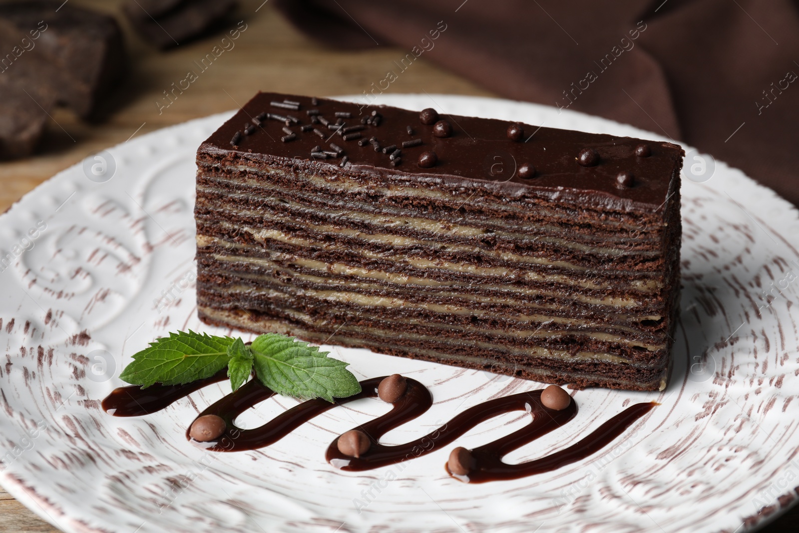 Photo of Piece of tasty chocolate cake and mint on white plate, closeup