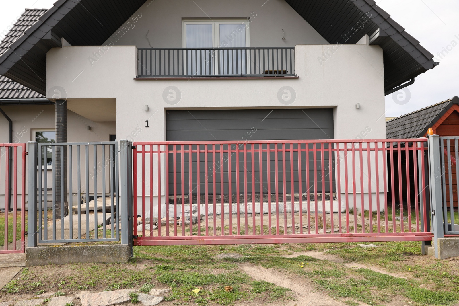 Photo of Red and grey metal gates near private house on street