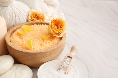 Sea salt, different spa products and beautiful roses on white marble table. Space for text