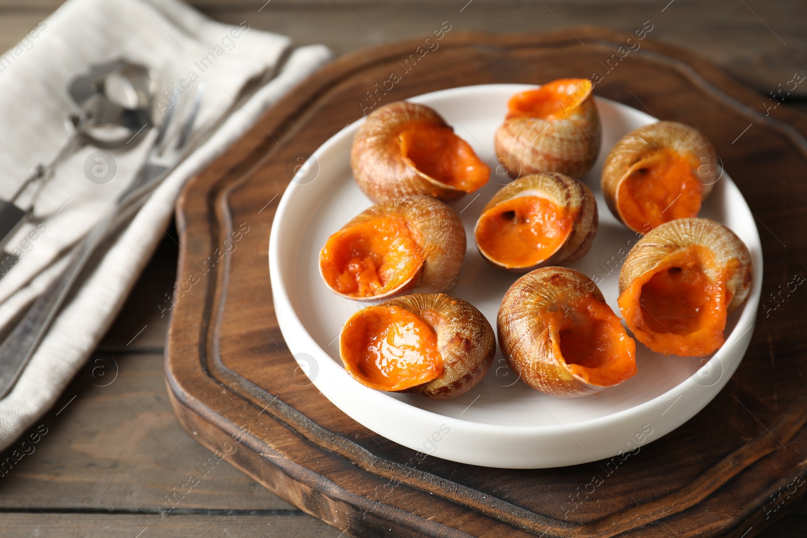 Photo of Delicious cooked snails on wooden table, closeup