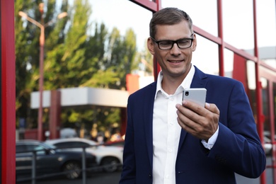 Businessman with modern smartphone on city street
