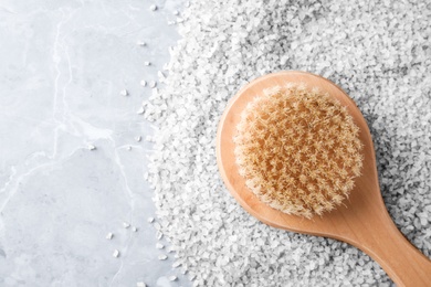 Photo of Salt for spa scrubbing procedure and brush on grey marble background, top view