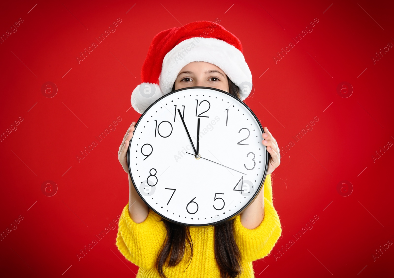 Photo of Girl in Santa hat with clock on red background. New Year countdown