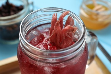 Mason jar of delicious iced hibiscus tea on table, closeup