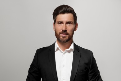 Portrait of handsome bearded man in suit on light grey background