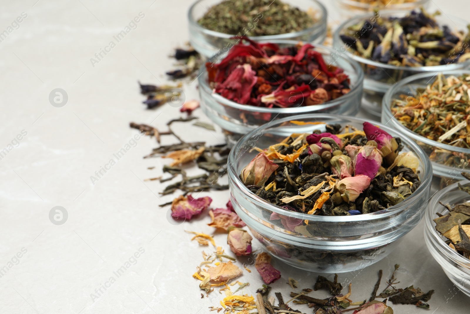 Photo of Different dry aromatic teas on light table, space for text