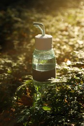 Photo of Glass bottle of water in green grass on sunny day