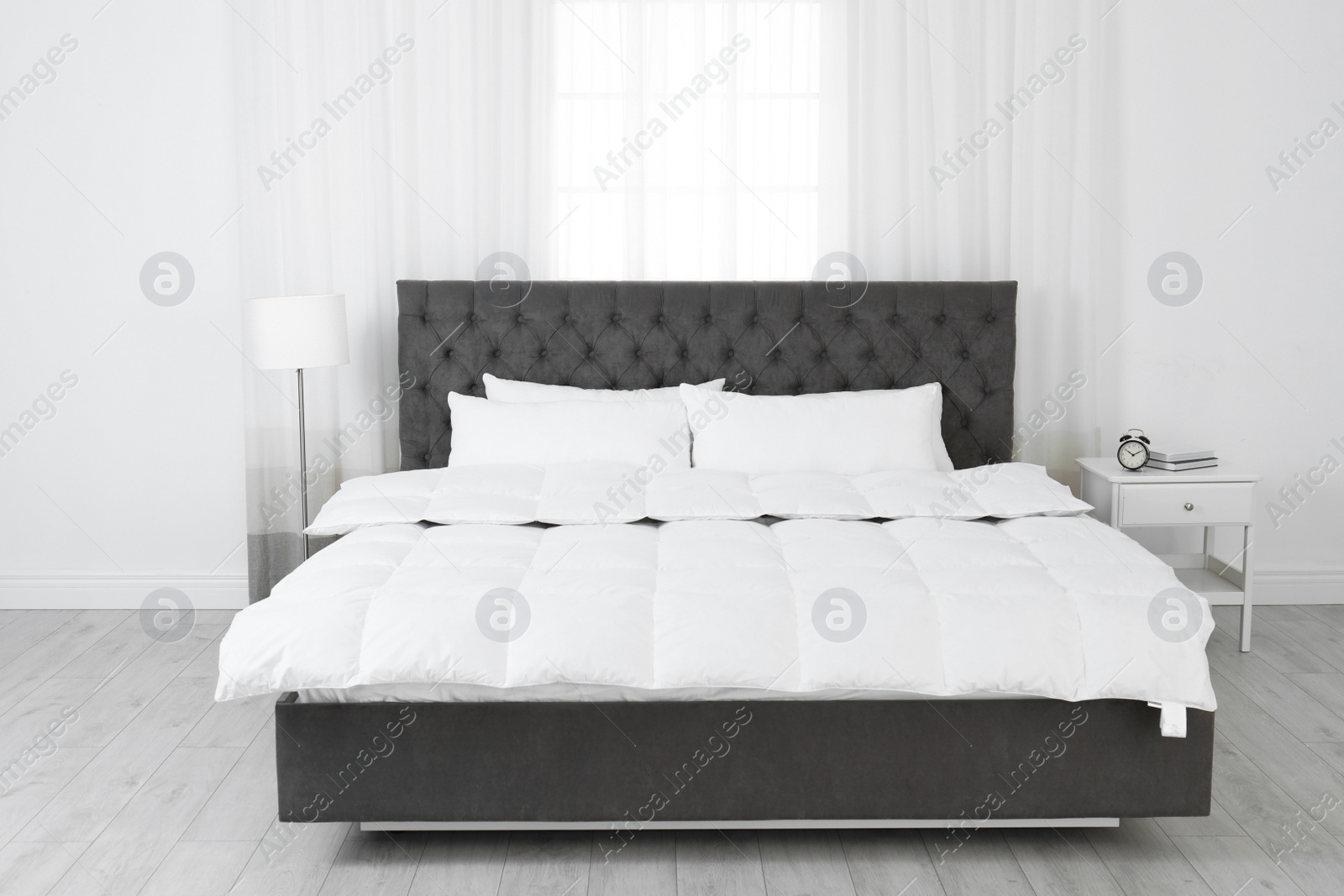 Photo of Large comfortable bed in light room. Stylish interior