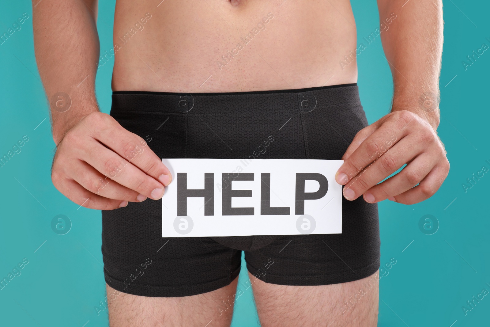 Photo of Man holding paper with word HELP on turquoise background, closeup. Urology problems