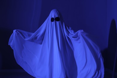 Creepy ghost. Woman covered with sheet in blue light