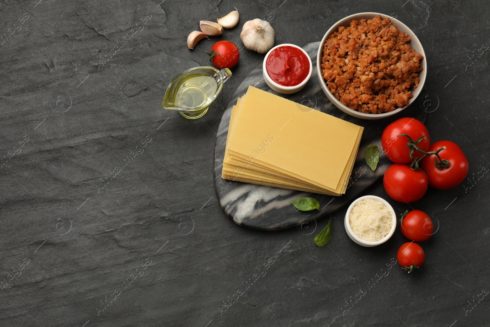 Photo of Flat lay composition with products for cooking lasagna on dark textured table. Space for text