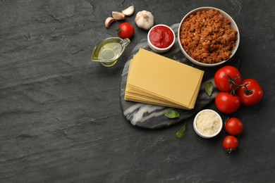 Photo of Flat lay composition with products for cooking lasagna on dark textured table. Space for text