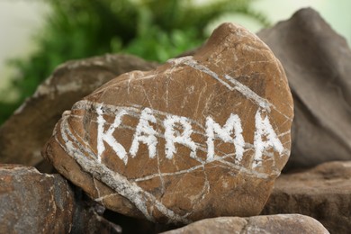 Photo of Stone with word Karma on blurred background, closeup