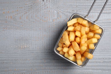 Tasty French fries on grey wooden table, top view. Space for text