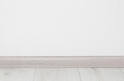Wooden plinth on laminated floor near white wall indoors