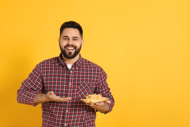 Photo of Young man with French fries on orange background, space for text