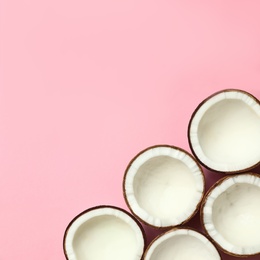 Fresh coconut halves on pink background, flat lay. Space for text