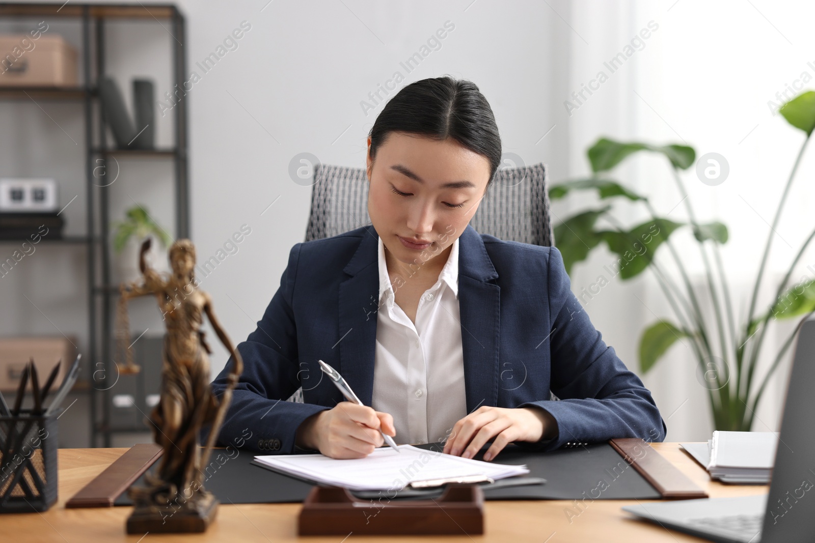 Photo of Notary signing document at table in office