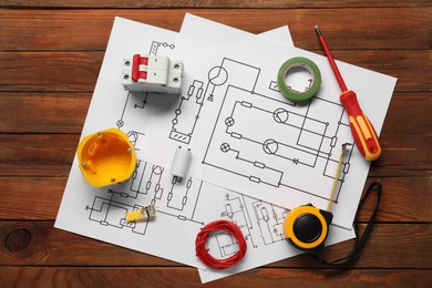 Photo of Wiring diagrams, screwdriver and different electrician's equipment on wooden table, flat lay
