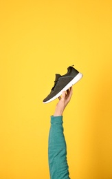 Photo of Man holding stylish shoe on yellow background, closeup