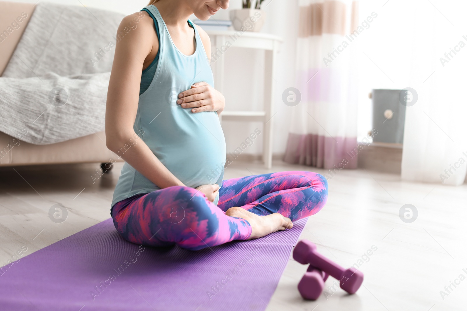 Photo of Young pregnant woman doing exercises at home