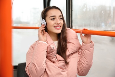 Beautiful young woman listening to music with headphones in public transport