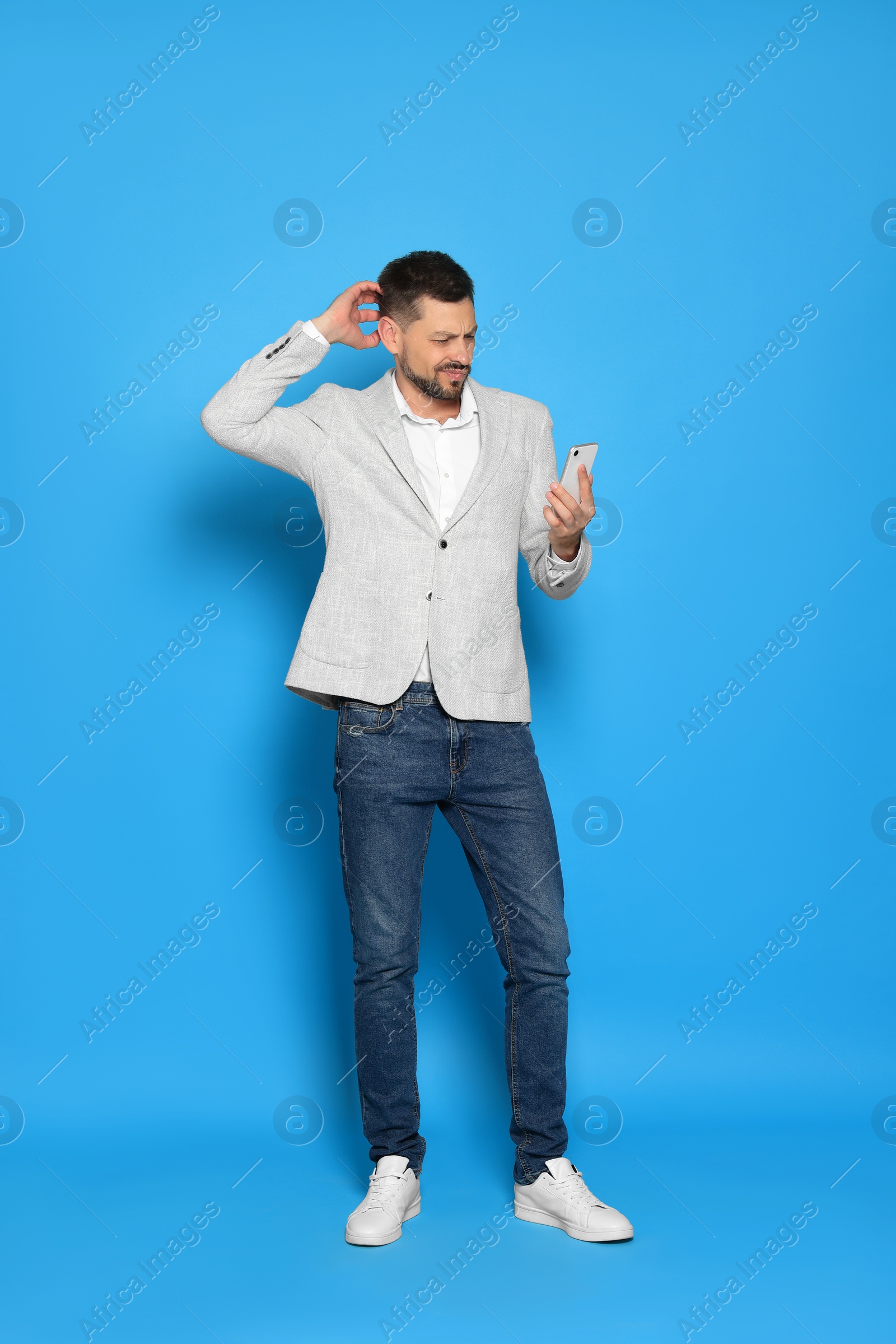 Photo of Handsome man looking at smartphone on light blue background