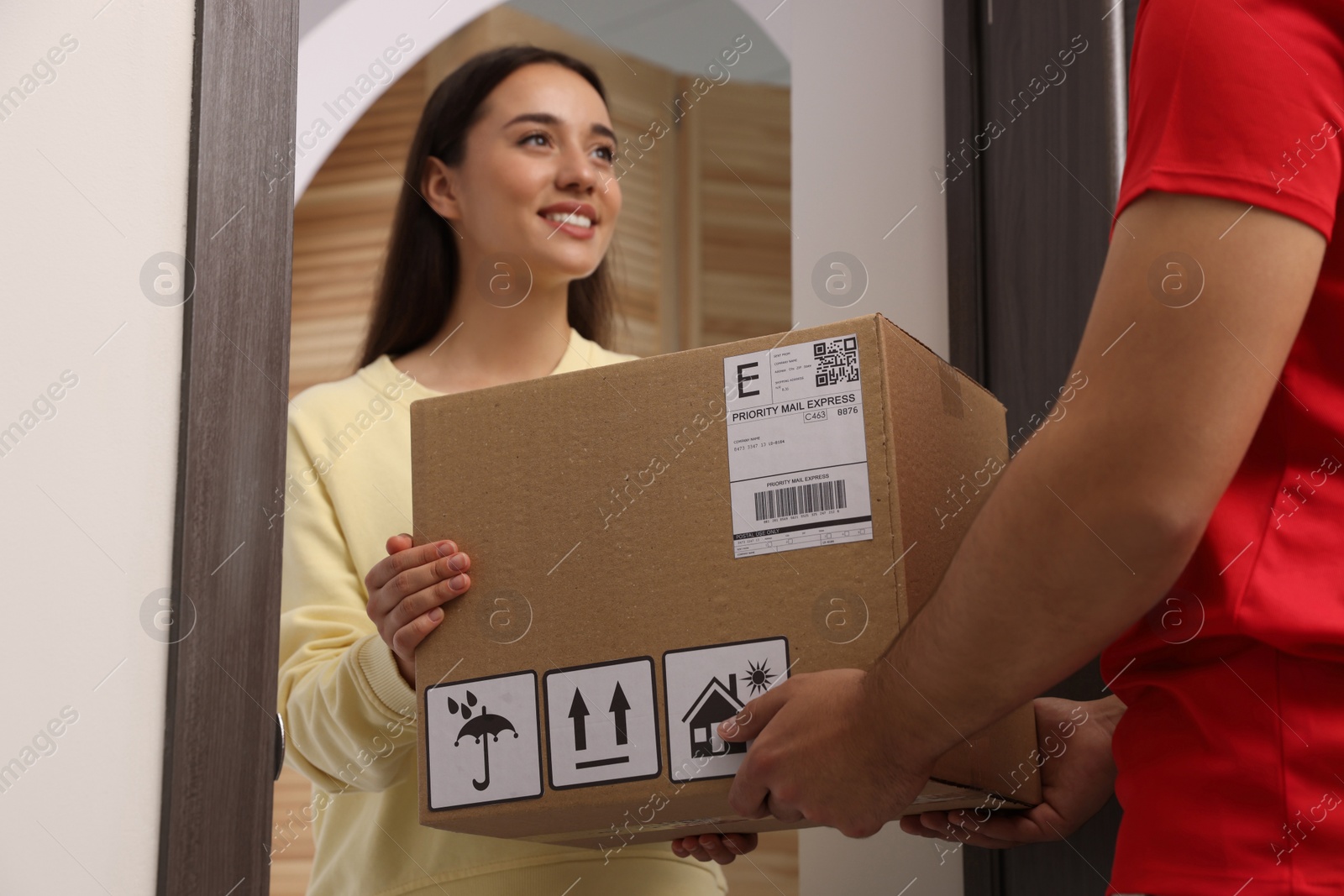 Photo of Woman receiving parcel from courier at home
