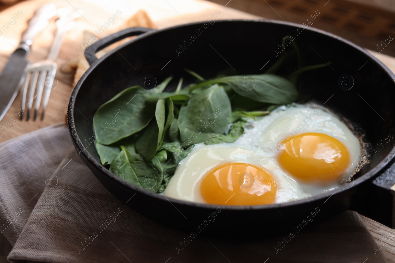 Photo of Delicious fried egg with spinach served on wooden table, closeup