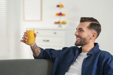 Photo of Handsome man with delicious smoothie on sofa at home