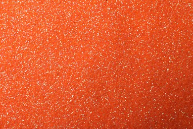 Photo of Beautiful shiny orange glitter as background, closeup