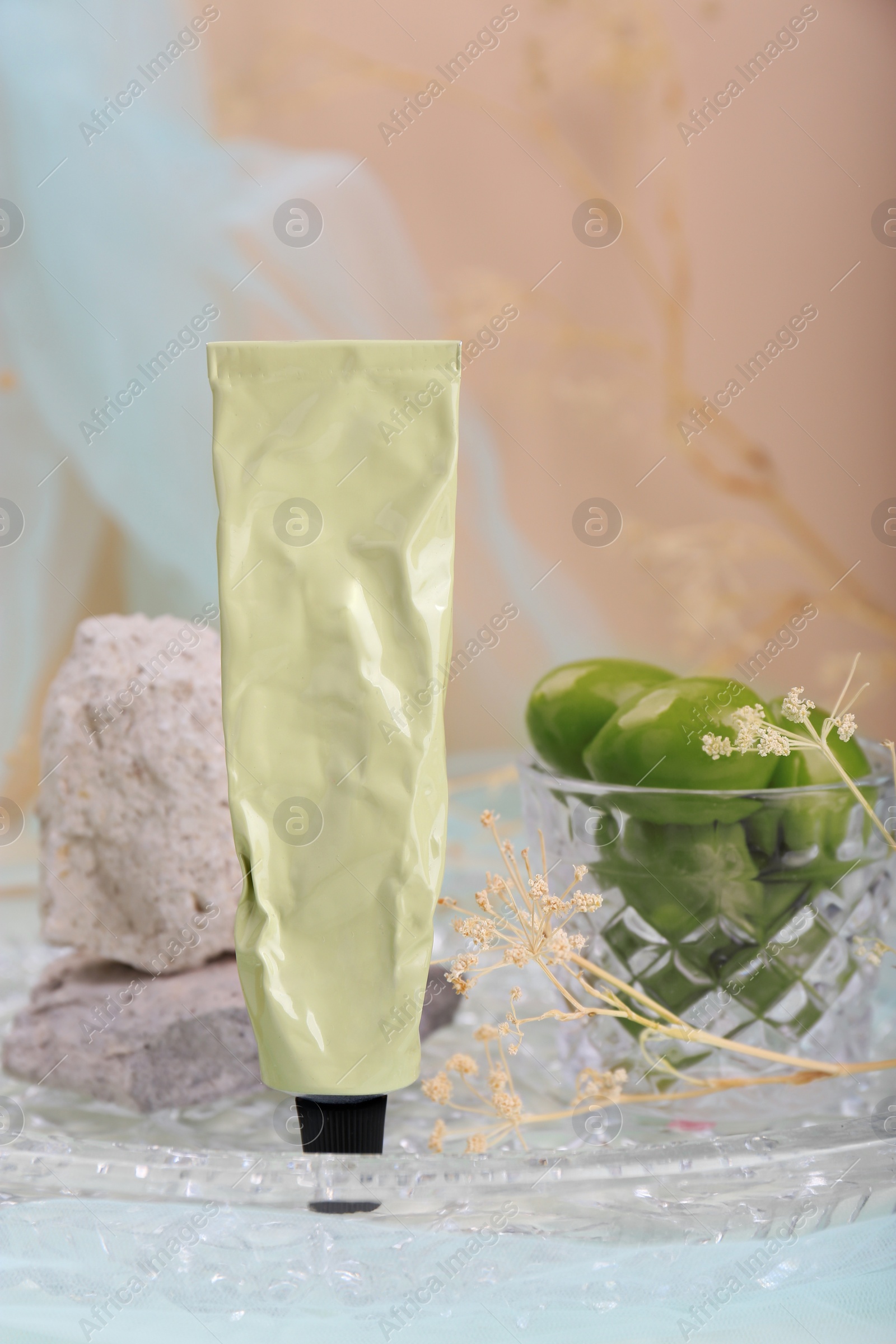 Photo of Tube of cream, olives and stones in glass tray