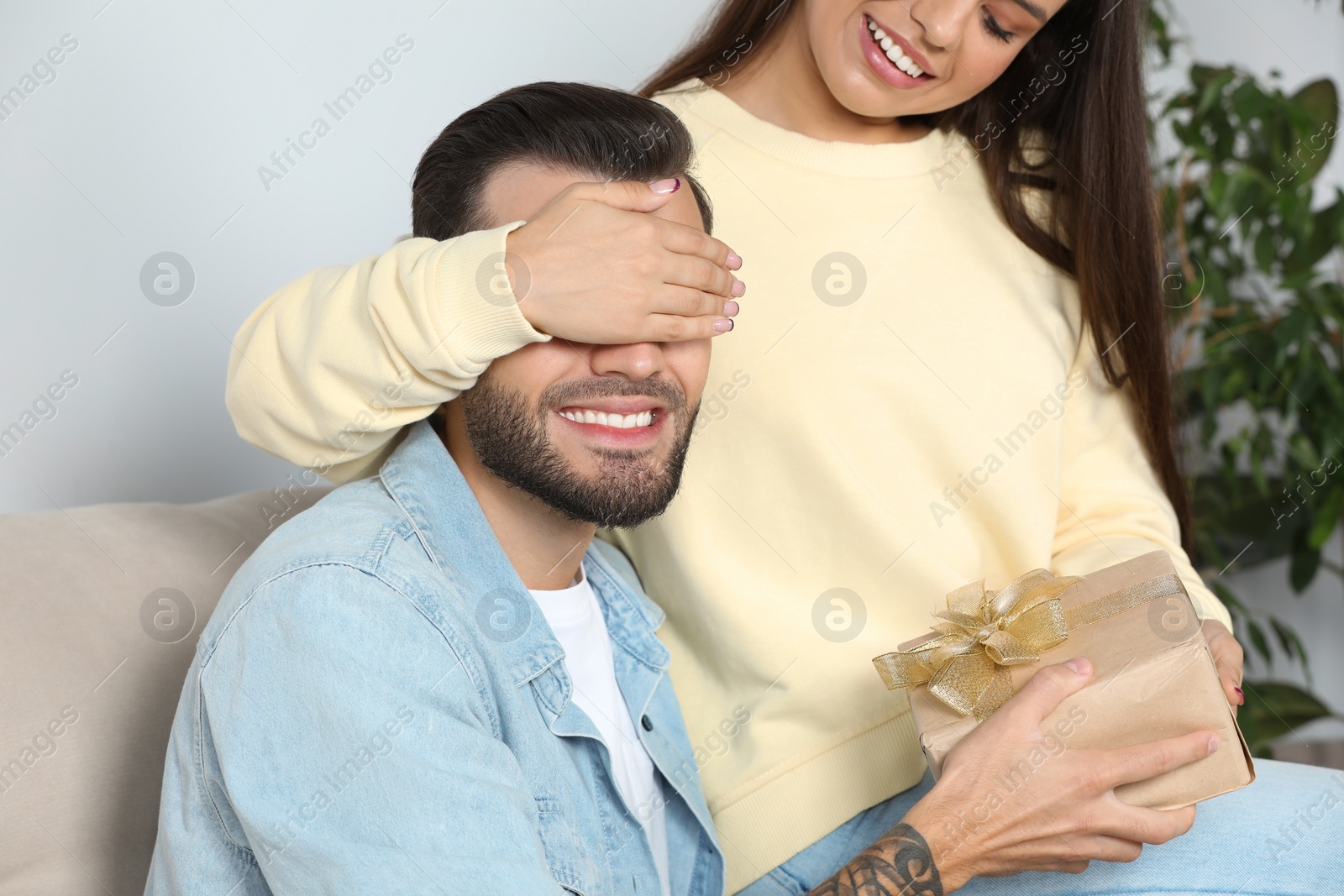 Photo of Woman presenting gift to her boyfriend at home