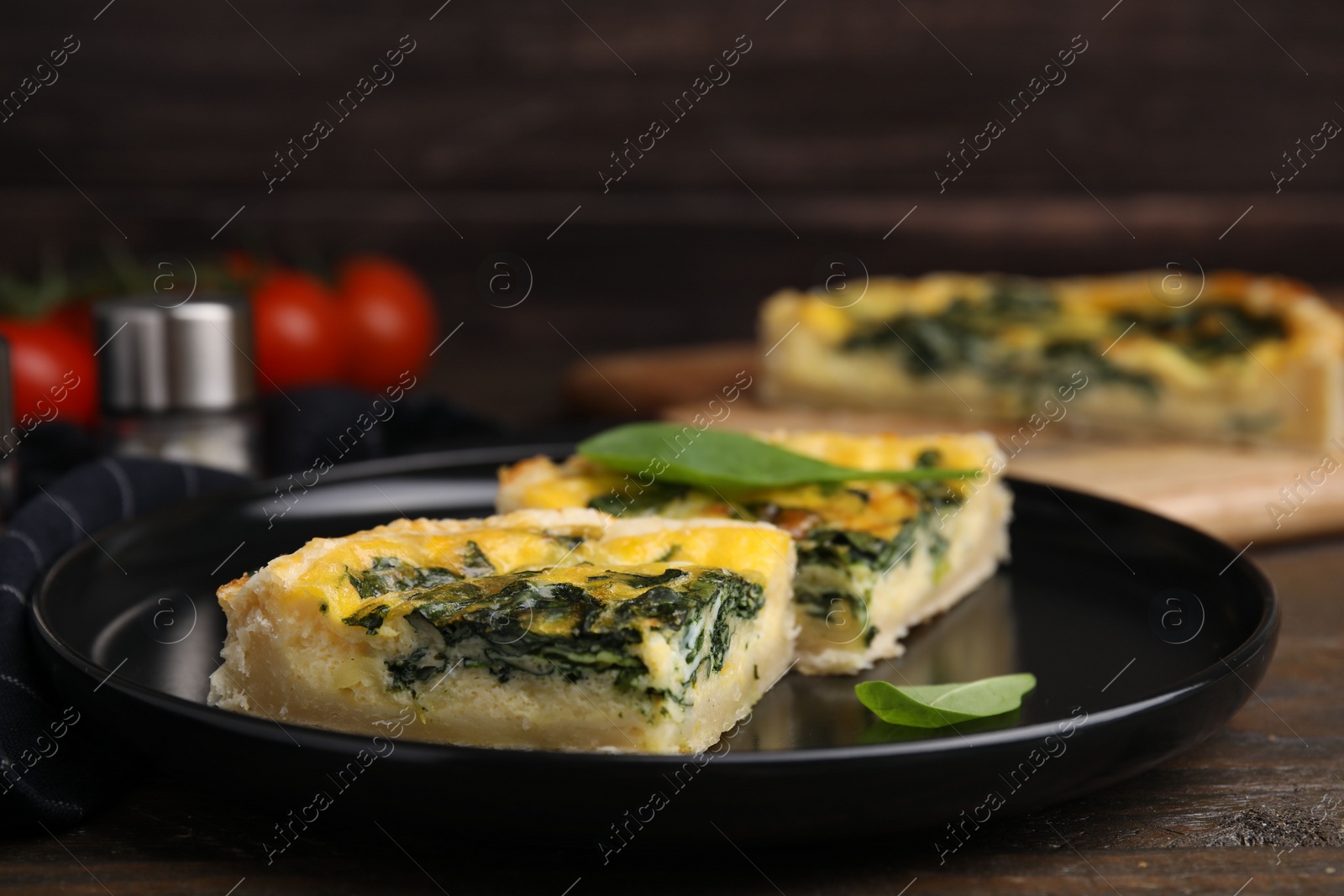 Photo of Pieces of delicious pie with spinach on wooden table, closeup