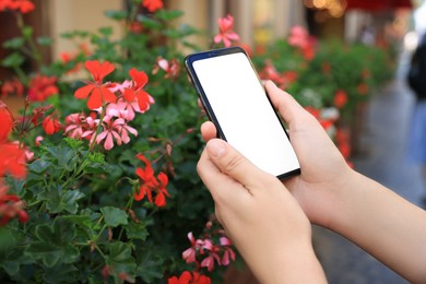 Photo of Closeup view of woman with smartphone near beautiful flowers outdoors