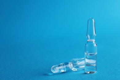 Photo of Two medical ampoules with solution on blue background. Space for text