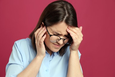 Photo of Young woman suffering from migraine on crimson background