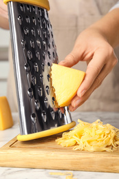 Photo of Woman grating fresh cheese at table, closeup