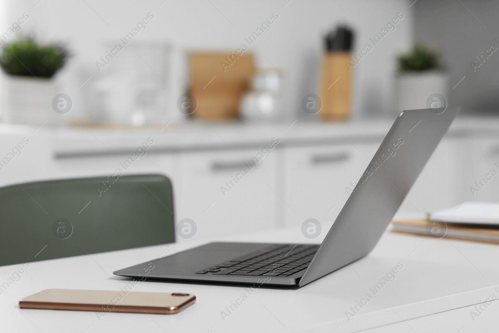 Photo of Home office. Laptop and smartphone on white desk in kitchen, space for text