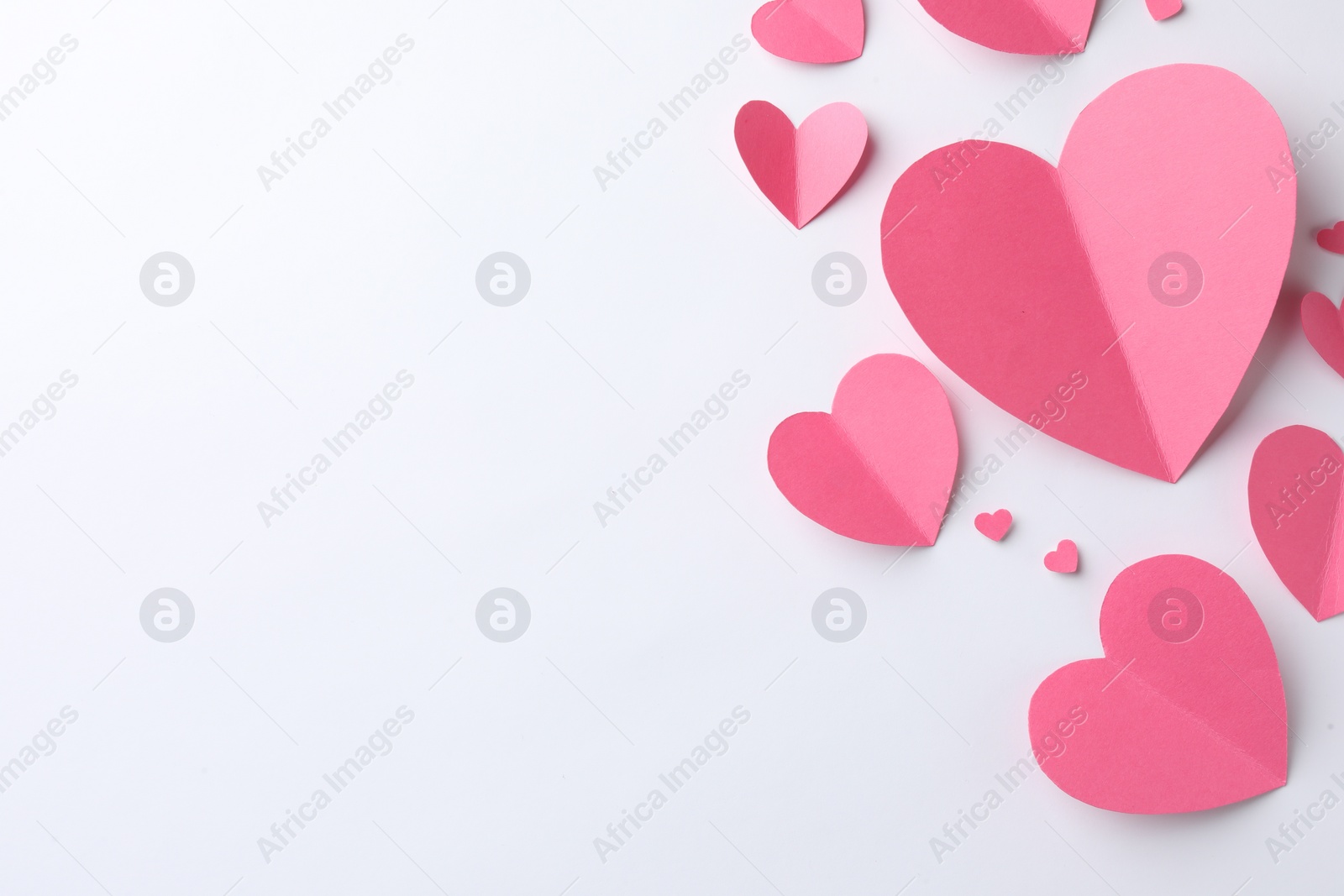 Photo of Pink paper hearts on white background, flat lay. Space for text