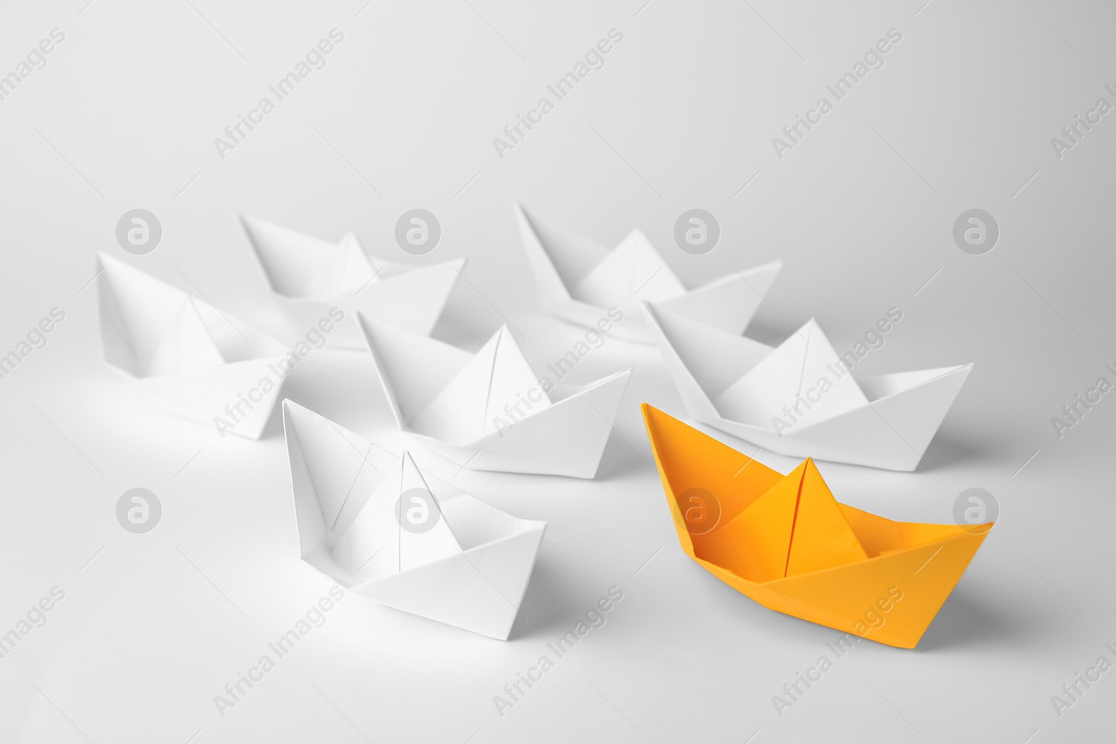 Photo of Group of paper boats following orange one on white background. Leadership concept