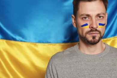 Man with face paint near Ukrainian flag. Space for text