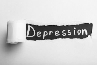 Photo of Word Depression on black background, view through hole in torn white paper