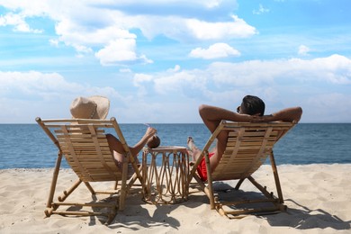 Photo of Couple resting in wooden sunbeds on tropical beach