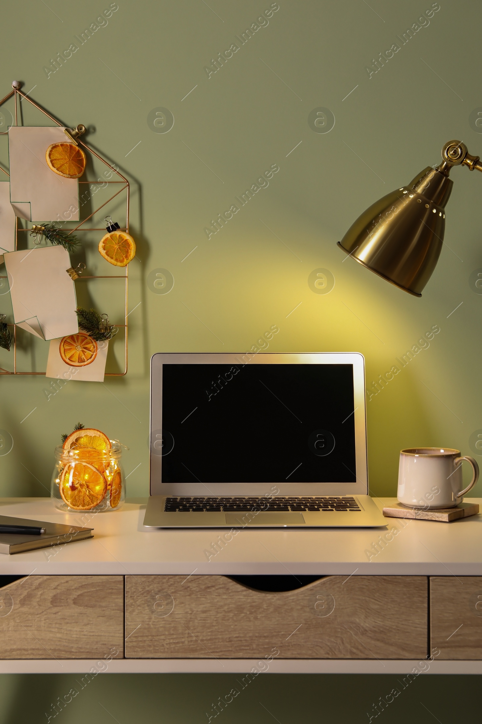 Photo of Stylish workplace with handmade decor made of dry orange slices and notes