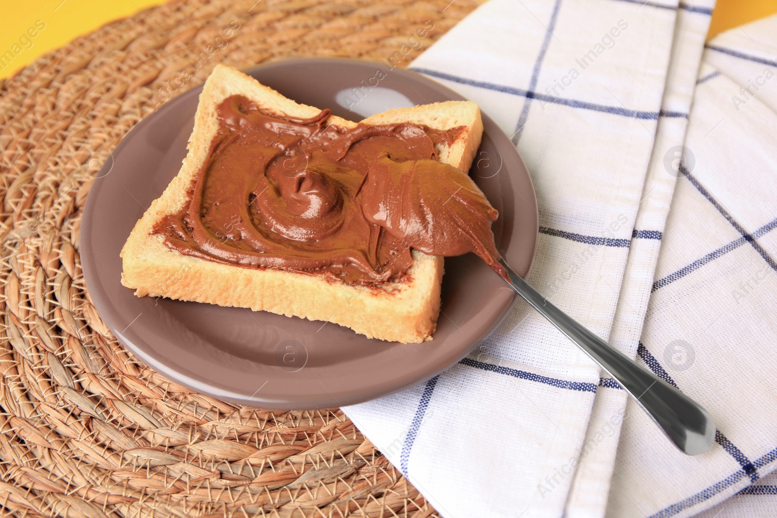 Photo of Tasty toast with chocolate paste on wicker mat