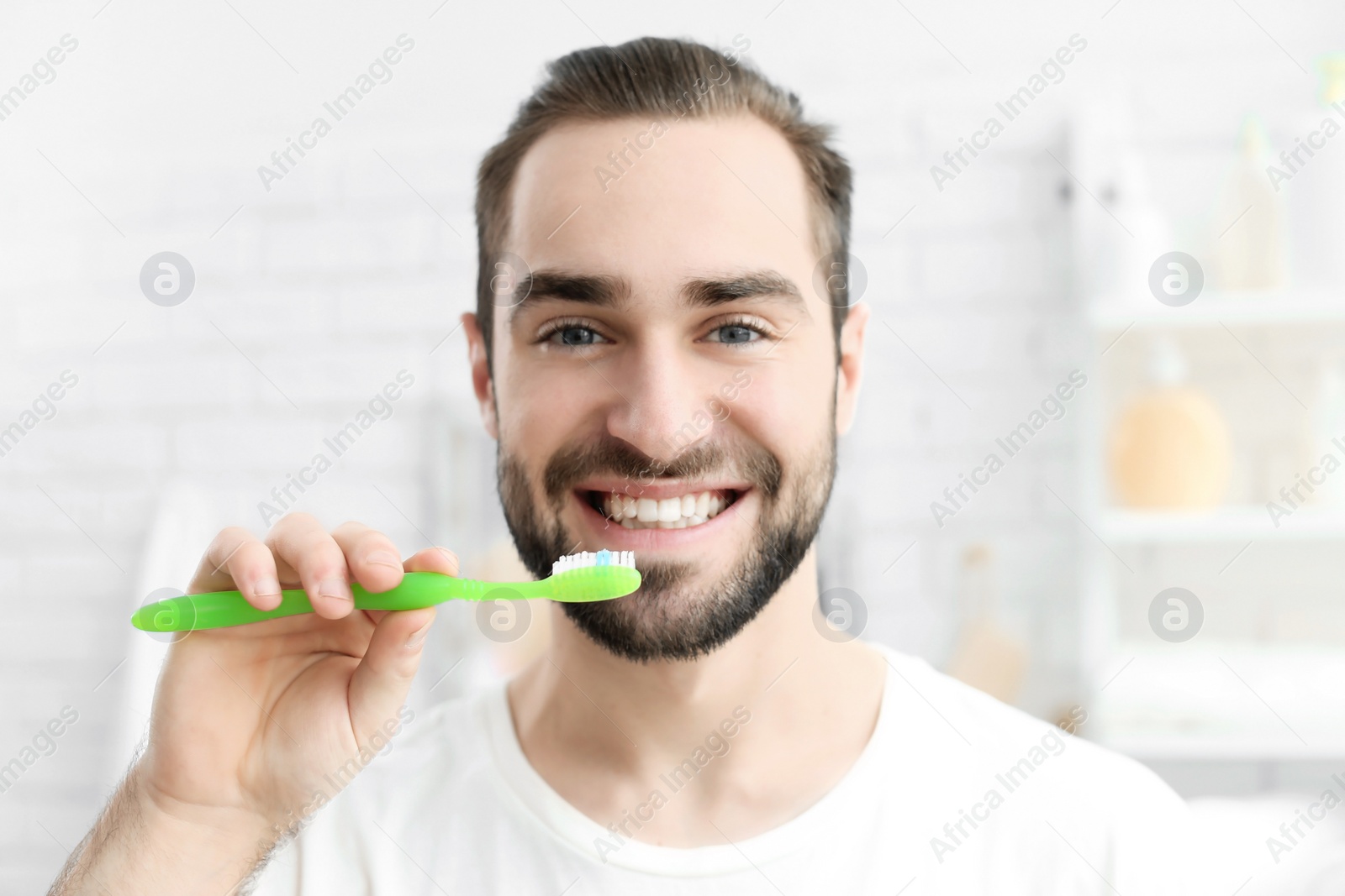 Photo of Young man brushing his teeth indoors