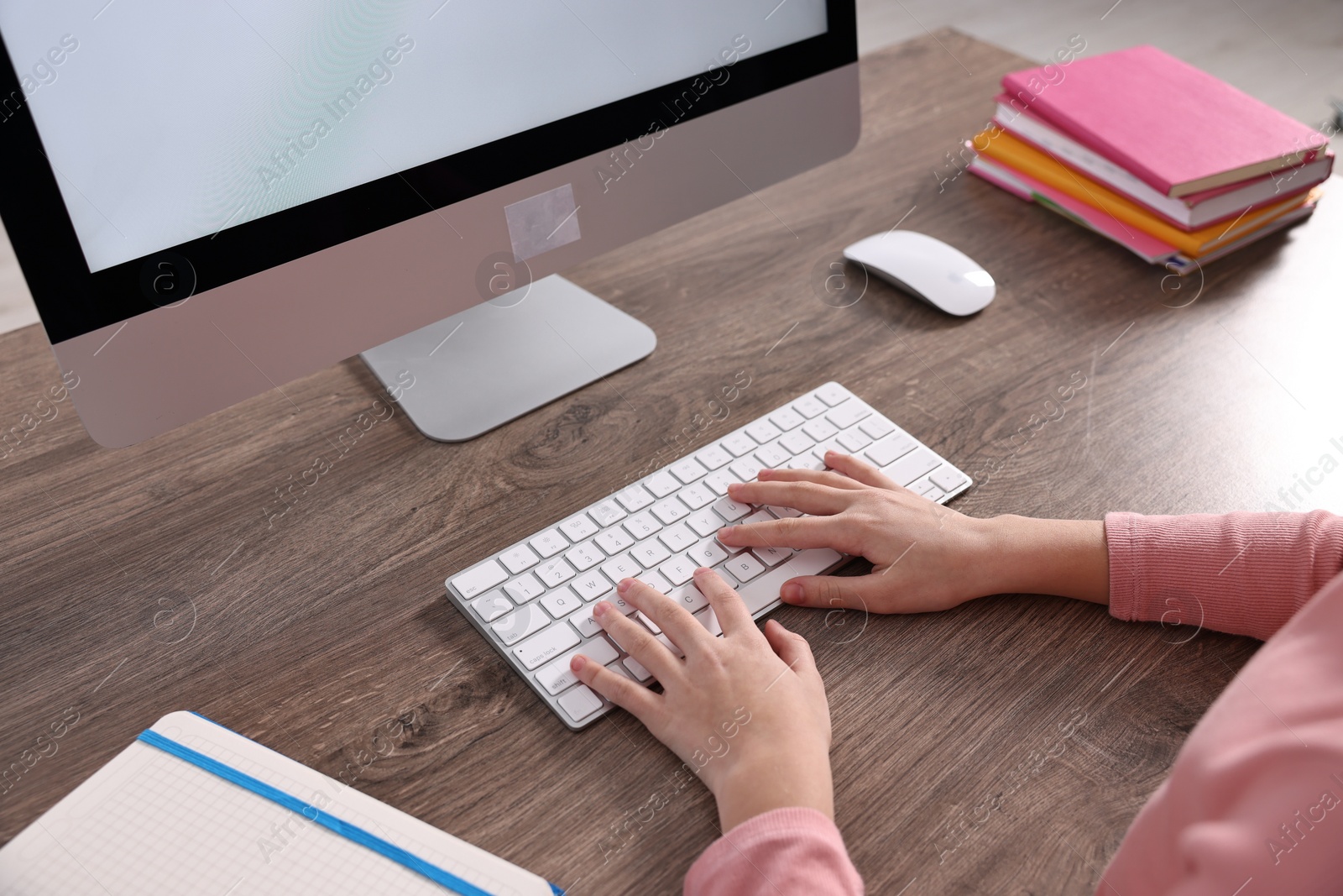 Photo of E-learning. Girl using computer during online lesson at table indoors, closeup