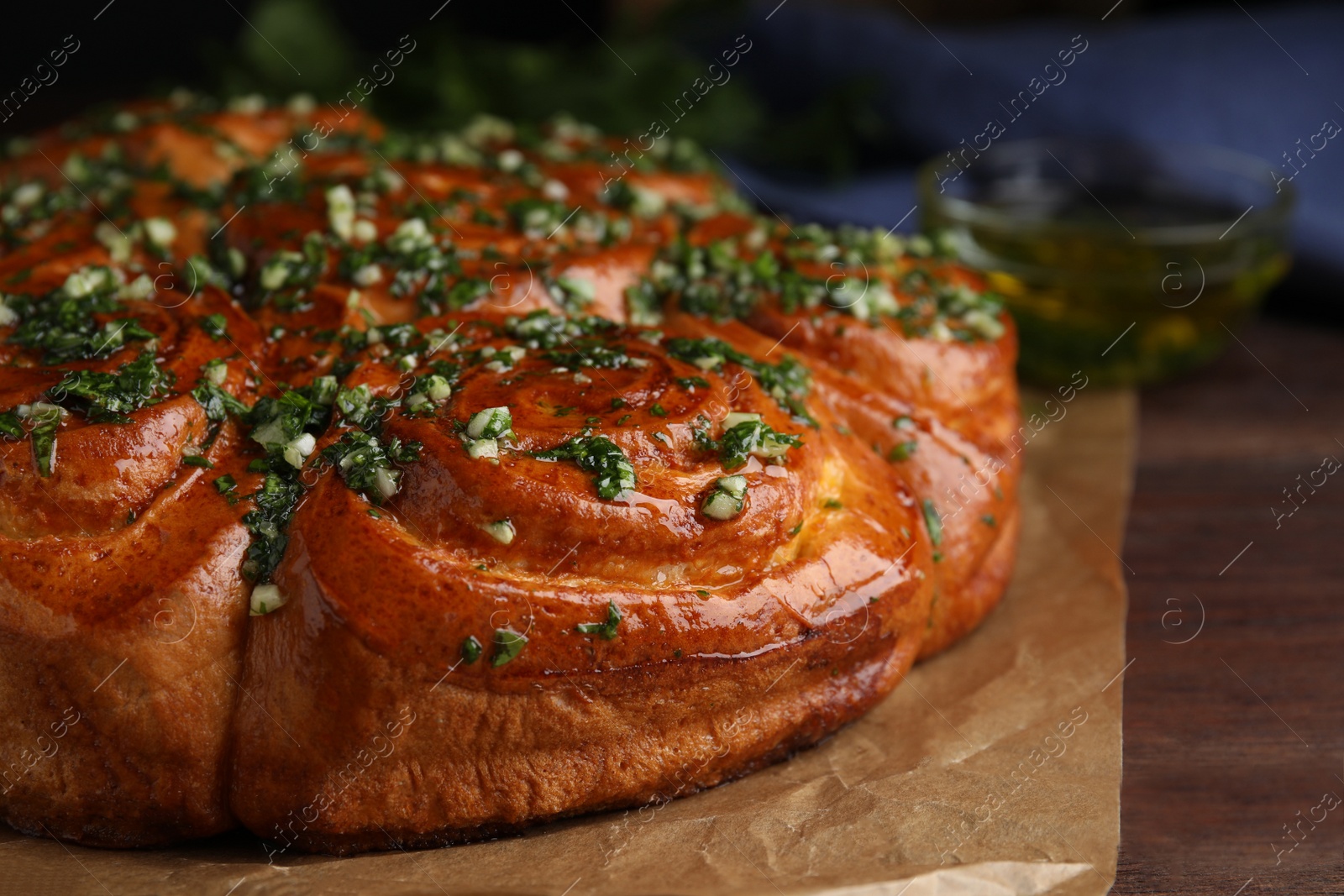 Photo of Traditional Ukrainian garlic bread with herbs (Pampushky) on wooden table, closeup