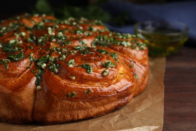 Photo of Traditional Ukrainian garlic bread with herbs (Pampushky) on wooden table, closeup